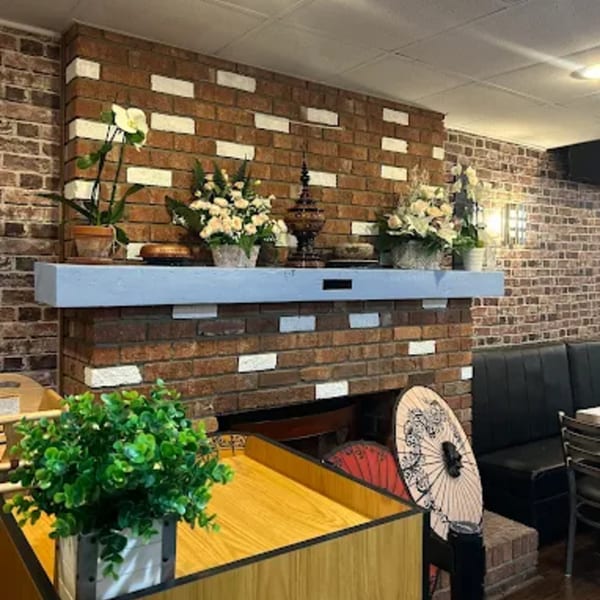 A brick fireplace with a light blue mantelpiece adorned with flowers and decorative items.