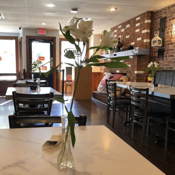 Interior of Road To Myanmar Asian Cuisine, featuring dining tables, chairs, and a brick wall.